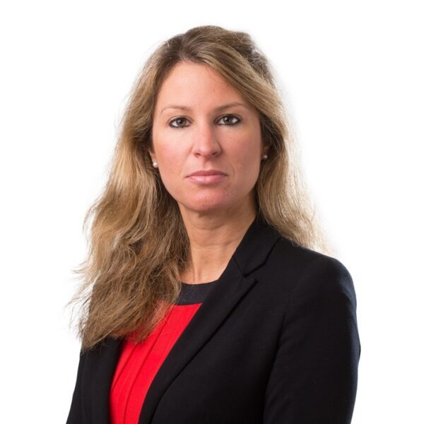 Professional portrait of a woman with wavy long brown hair, she is wearing a black blazer.