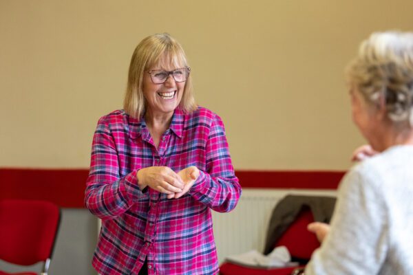 Woman with blonde hair, smiling a holding something in her hands.