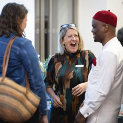 Three people having a conversation. On lady in the centre appears to be laughing.