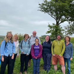 Eight people out on a walk, all are smiling at the camera