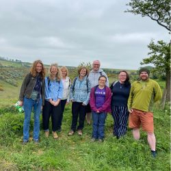 7 people stood outside on a walk, all are smiling at the camera
