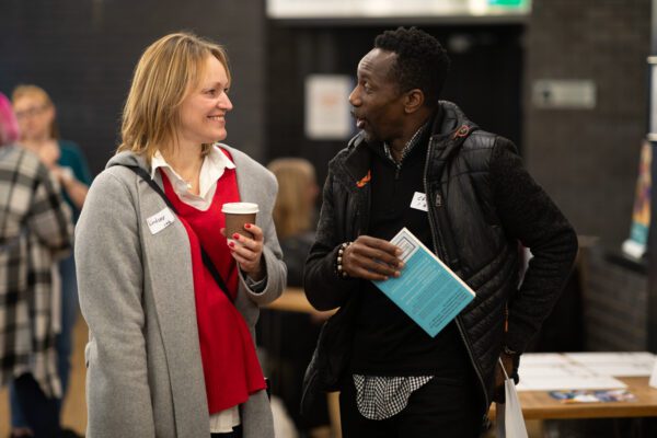 Two adults talking at an indoor event.