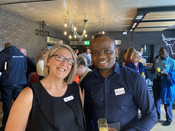 Two adults smiling at an indoor event.