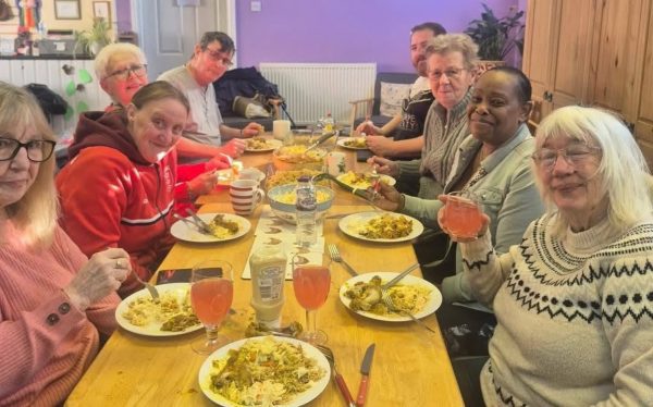 Group of people sat around a table enjoying a warm meal